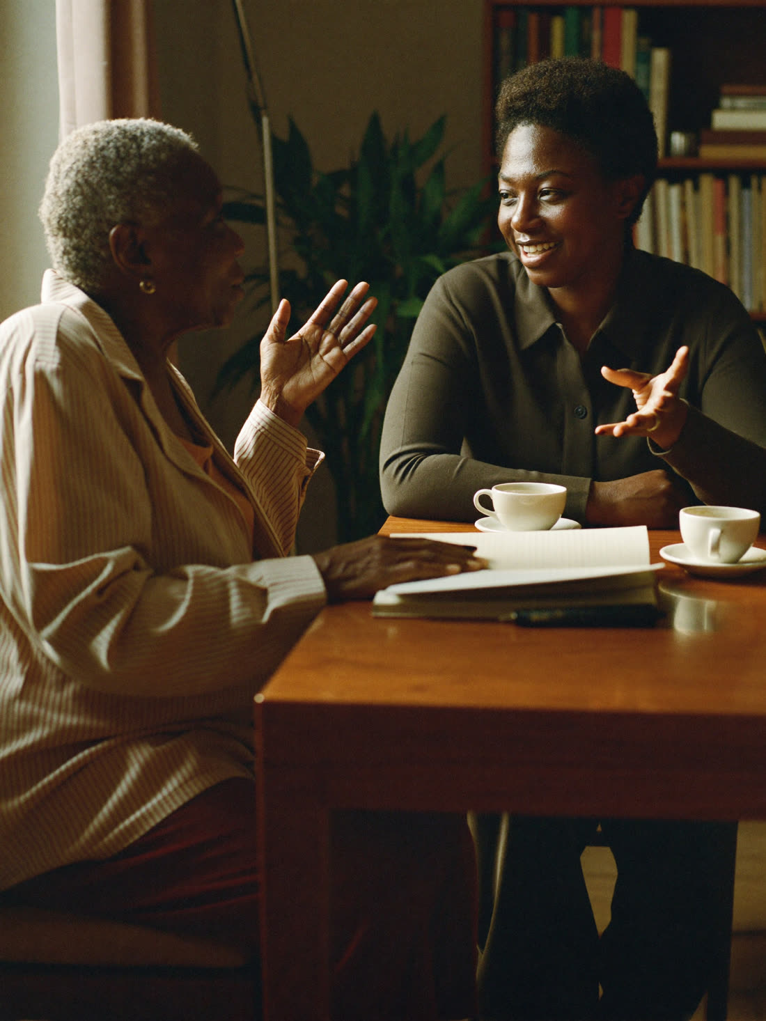Two women in conversation across a table at a SHUMI gathering